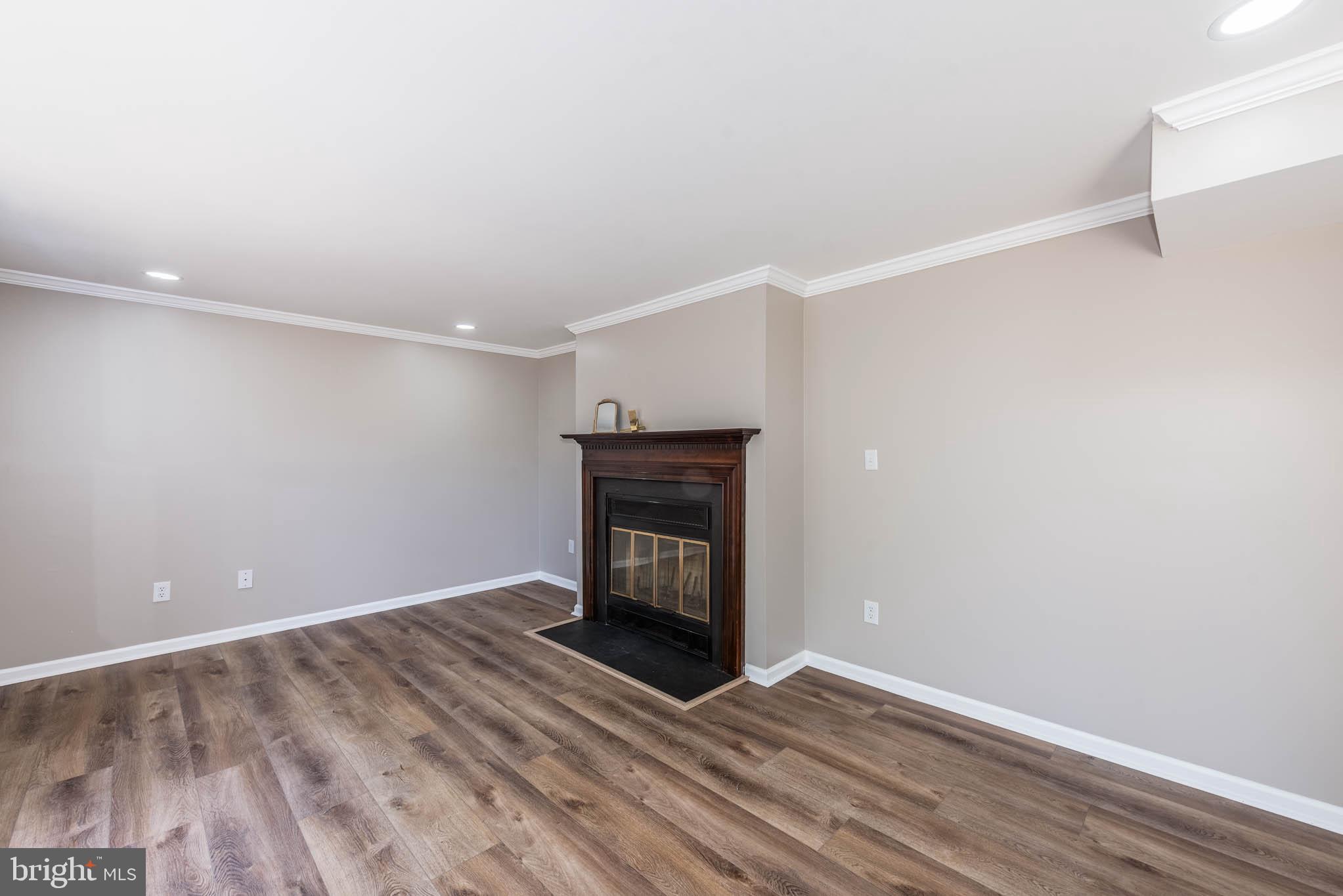 7674 Tuckerman Drive Hanover, MD 21076 - Photo 12 of 45 a view of an empty room with wooden floor fireplace and a window