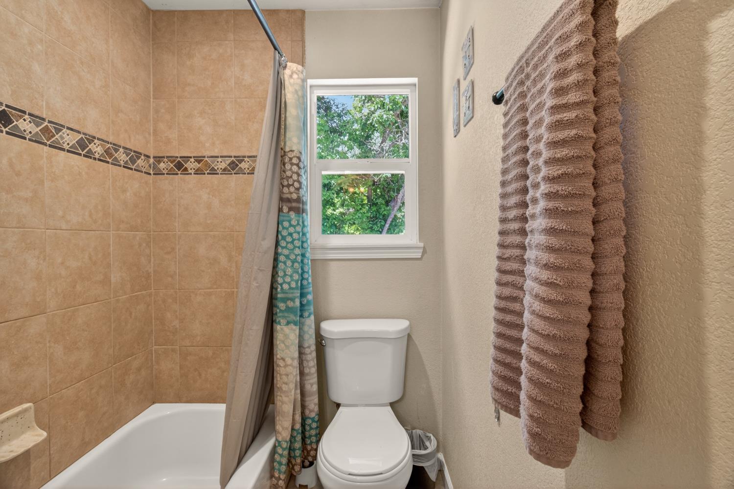 6332 Horseshoe Bar Road Loomis, CA 95650 - Photo 26 of 85 Bathroom featuring a white bathtub, beige tile surround with decorative accent band, and a white framed window
