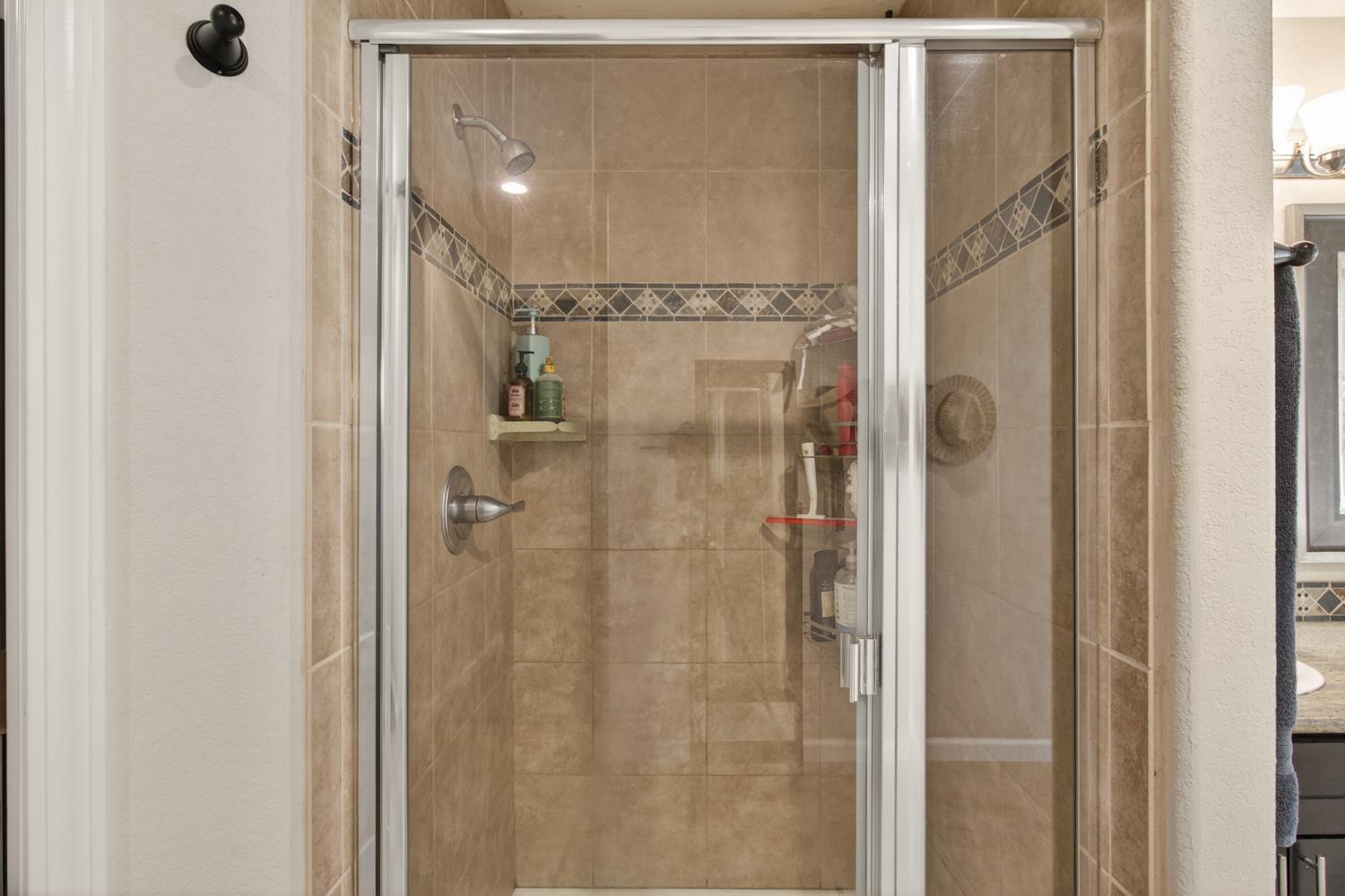 6332 Horseshoe Bar Road Loomis, CA 95650 - Photo 38 of 85 Glass-enclosed shower featuring large format tile, decorative accent band, satin nickel fixtures, and a recessed light