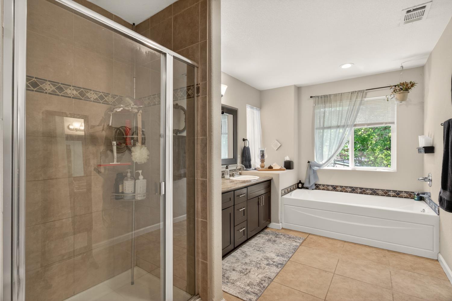 6332 Horseshoe Bar Road Loomis, CA 95650 - Photo 44 of 85 Bathroom featuring a glass-enclosed shower, a built-in soaking tub, and a dark wood-finish vanity with a single sink