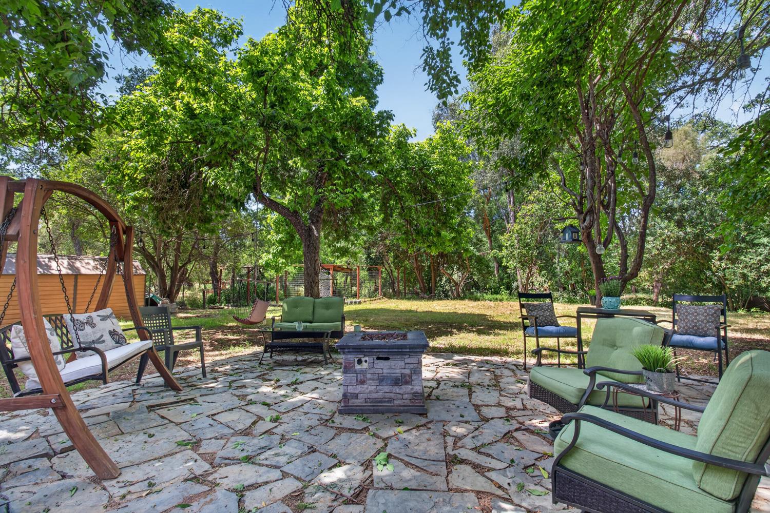 6332 Horseshoe Bar Road Loomis, CA 95650 - Photo 61 of 85 Expansive flagstone patio area featuring a stone-finish fire pit, surrounded by mature trees providing natural shade