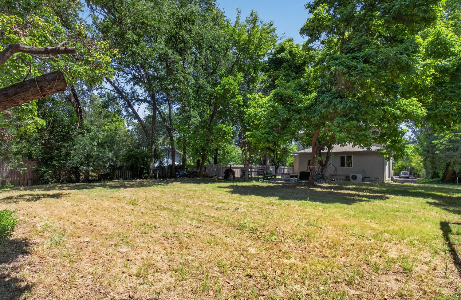 6332 Horseshoe Bar Road Loomis, CA 95650 - Photo 64 of 85 Expansive backyard featuring mature trees providing ample shade, a partial privacy fence, and a visible portion of the exterior siding