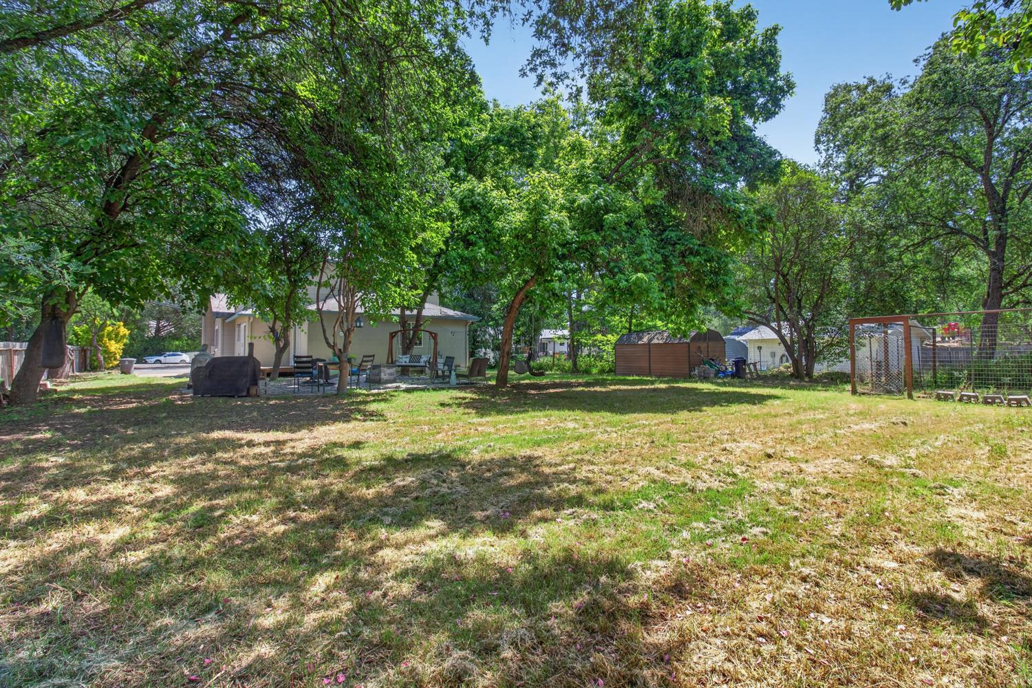6332 Horseshoe Bar Road Loomis, CA 95650 - Photo 65 of 85 Expansive backyard featuring mature trees, a stone patio, and a light-colored exterior dwelling