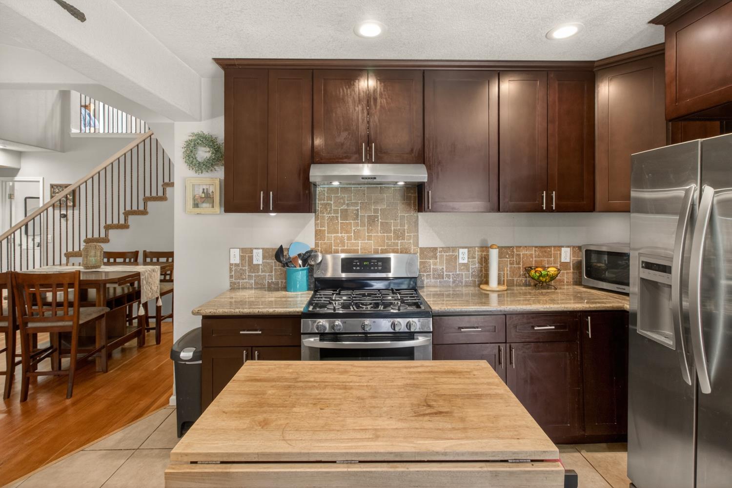 6332 Horseshoe Bar Road Loomis, CA 95650 - Photo 7 of 85 Kitchen featuring dark wood cabinetry, stainless steel appliances, a tile backsplash, and a light-toned countertop