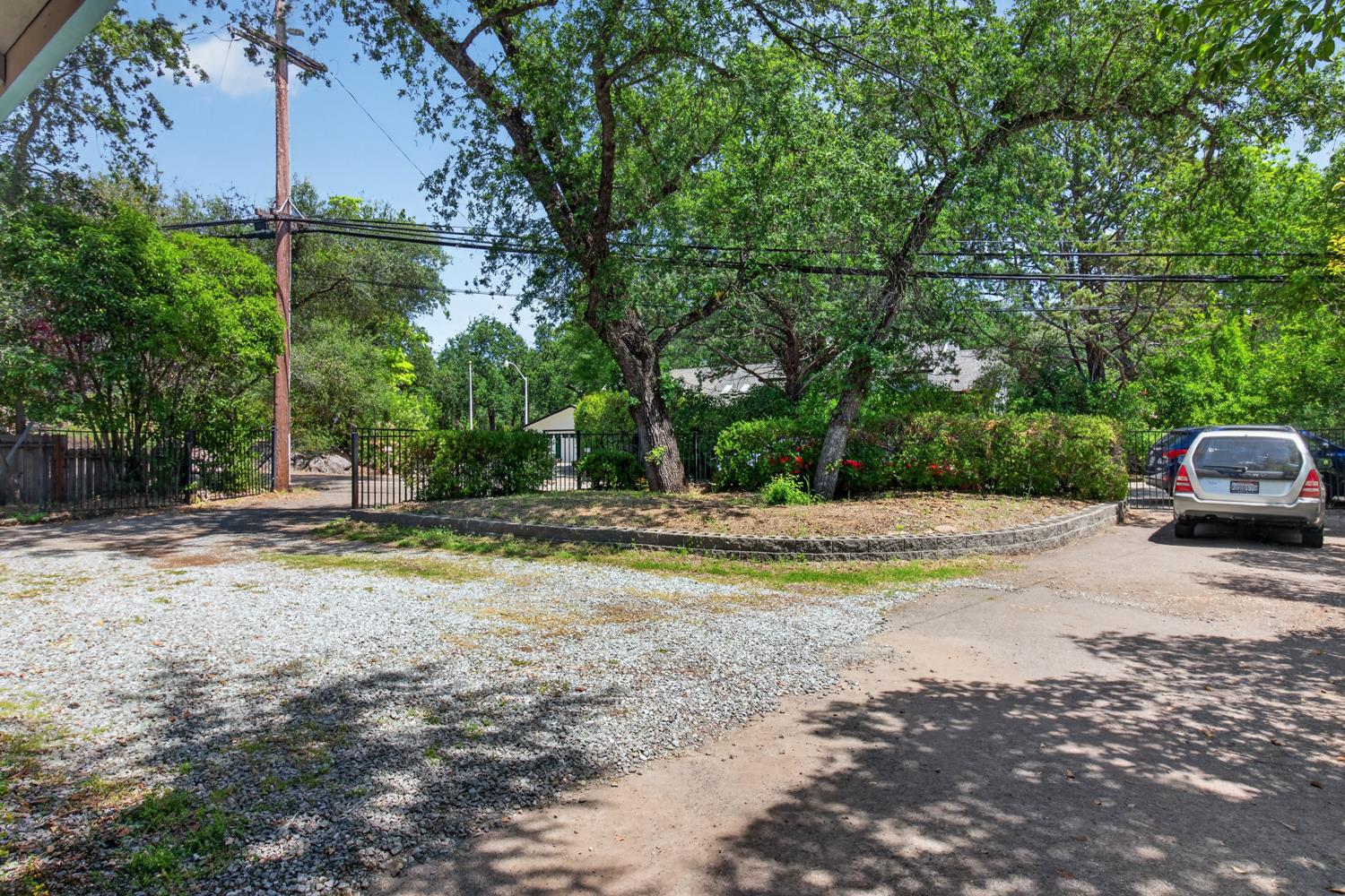 6332 Horseshoe Bar Road Loomis, CA 95650 - Photo 72 of 85 Gravel parking area featuring mature trees, a retaining wall, and a metal gate