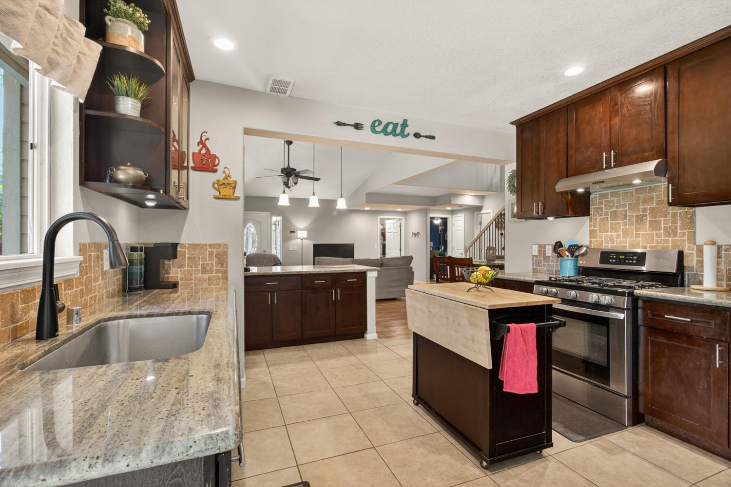 6332 Horseshoe Bar Road Loomis, CA 95650 - Photo 9 of 85 Kitchen featuring granite countertops, a stainless steel sink with a gooseneck faucet, a tile backsplash, and dark wood cabinetry