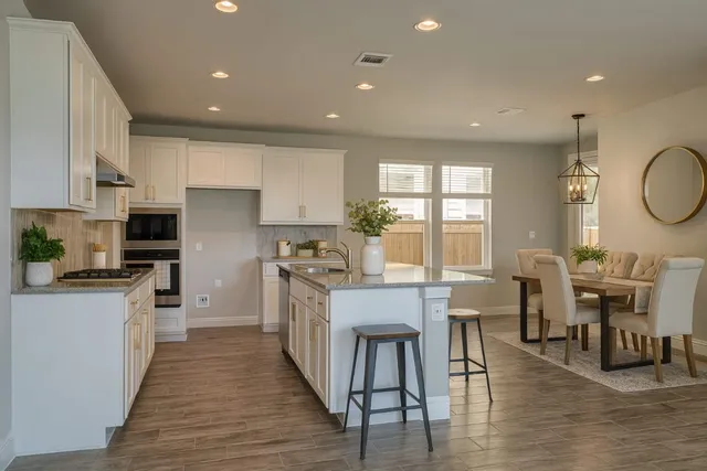 a large white kitchen with lots of counter space a sink appliances and dining table