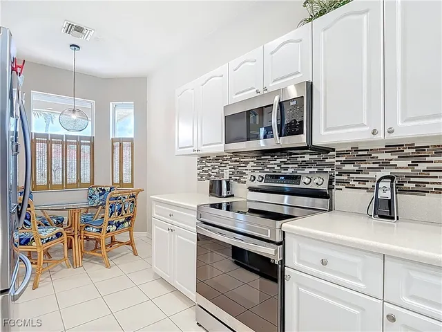 a kitchen with stainless steel appliances a stove a sink and white cabinets