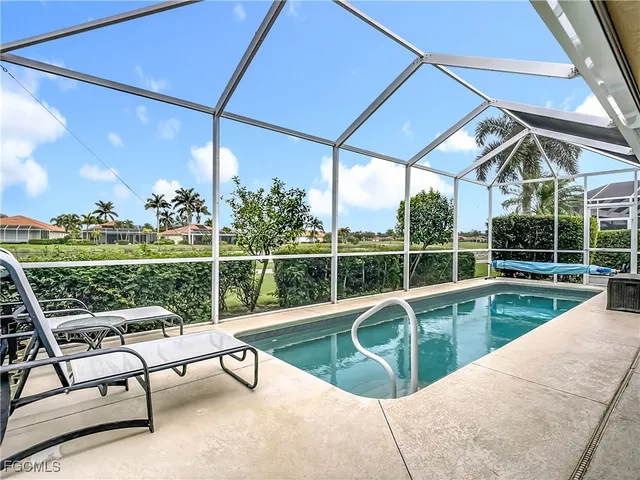 a view of a swimming pool with a couches chairs and wooden fence