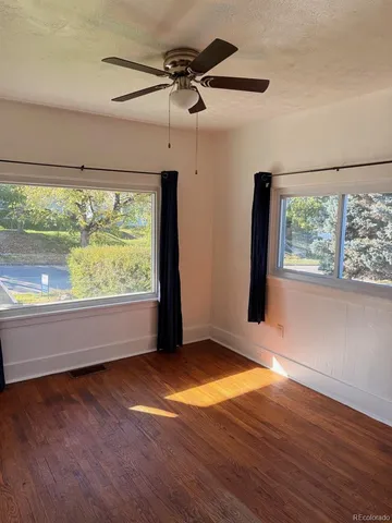 an empty room with wooden floor and windows