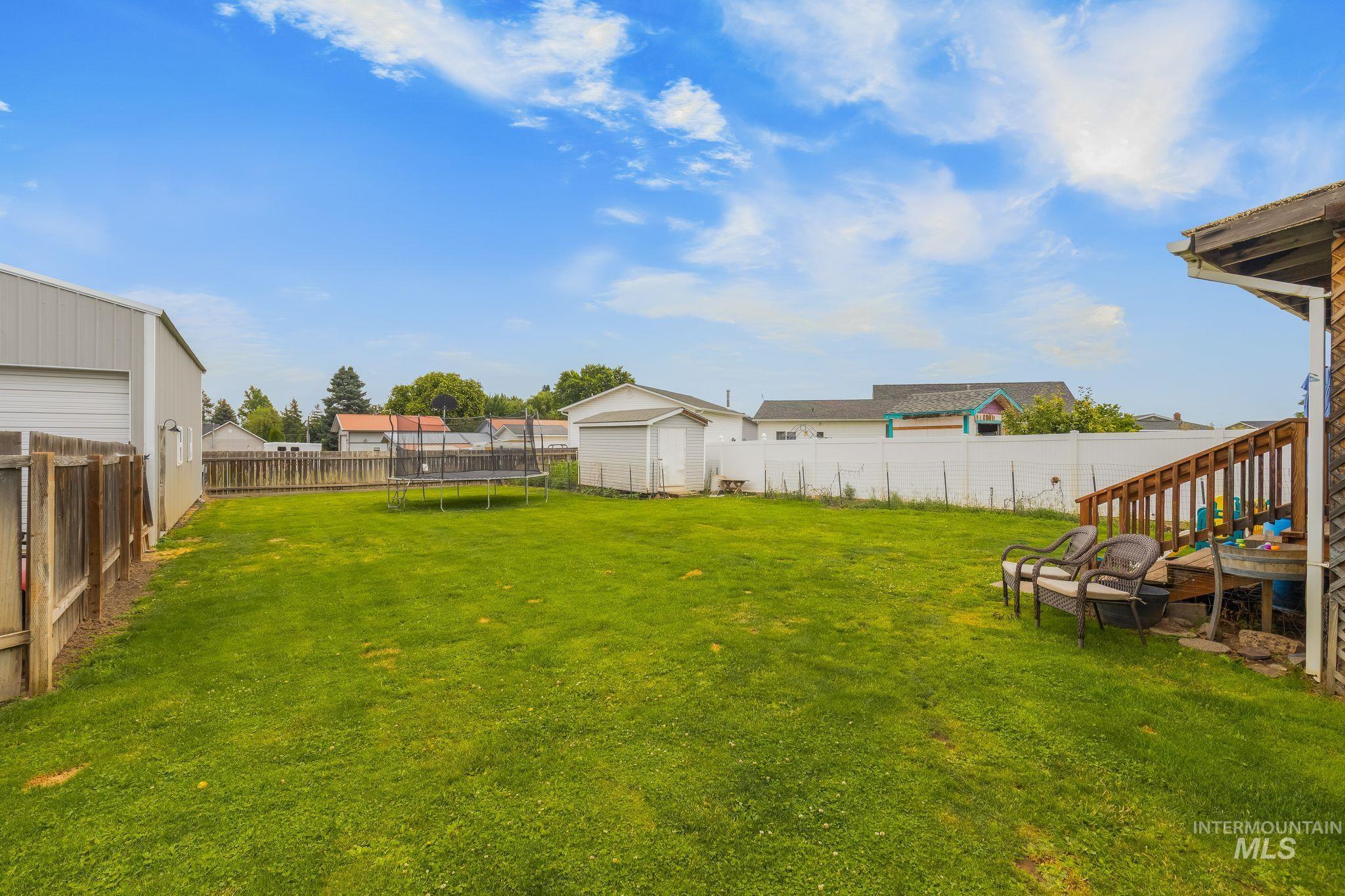2119 Ripon Avenue Lewiston, ID 83501 - Photo 37 of 50 Expansive green lawn backyard featuring a detached metal-sided outbuilding, a second storage shed, and a privacy fence