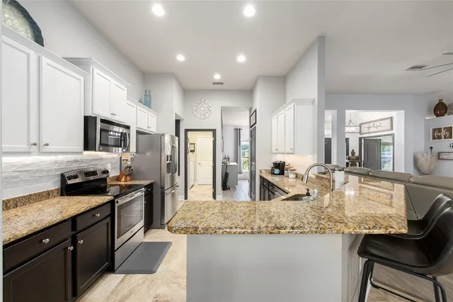 a kitchen with granite countertop kitchen island stainless steel appliances sink stove microwave and cabinets