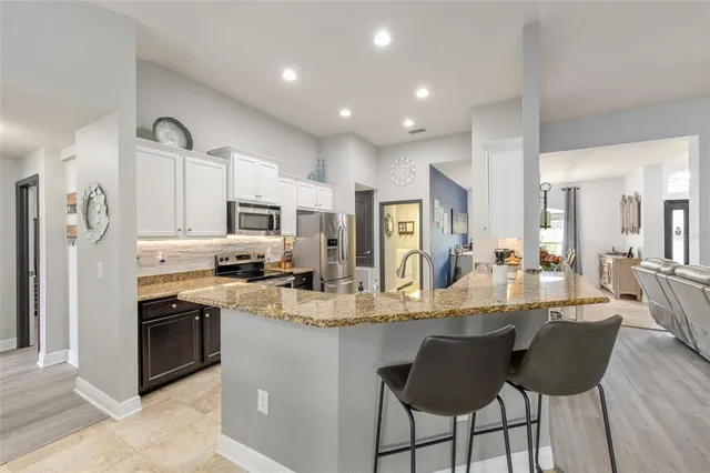 a large kitchen with granite countertop lots of counter top space and stainless steel appliances