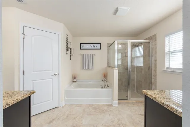 a spacious bathroom with a granite countertop tub shower and mirror