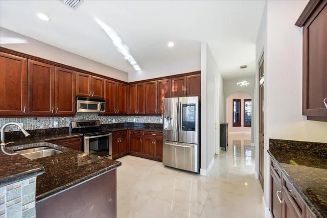 a kitchen with stainless steel appliances granite countertop a stove refrigerator and sink