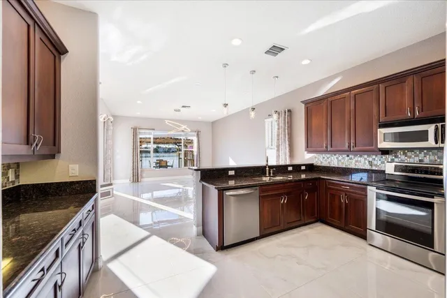 a kitchen with stainless steel appliances granite countertop wooden cabinets and a stove top oven