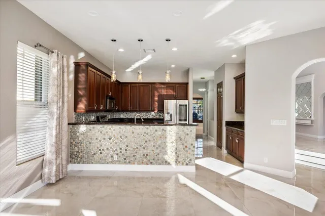 a large white kitchen with stainless steel appliances kitchen island granite countertop a refrigerator and cabinets