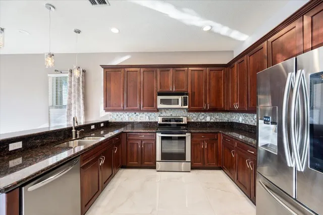 a kitchen with stainless steel appliances granite countertop a sink stove and refrigerator