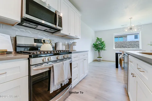 a kitchen with stainless steel appliances white cabinets and a stove top oven