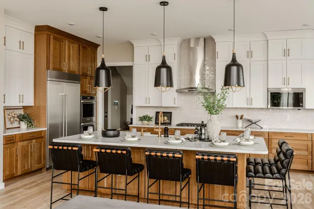 a kitchen with stainless steel appliances granite countertop a refrigerator a sink dishwasher a dining table and chairs with wooden floor