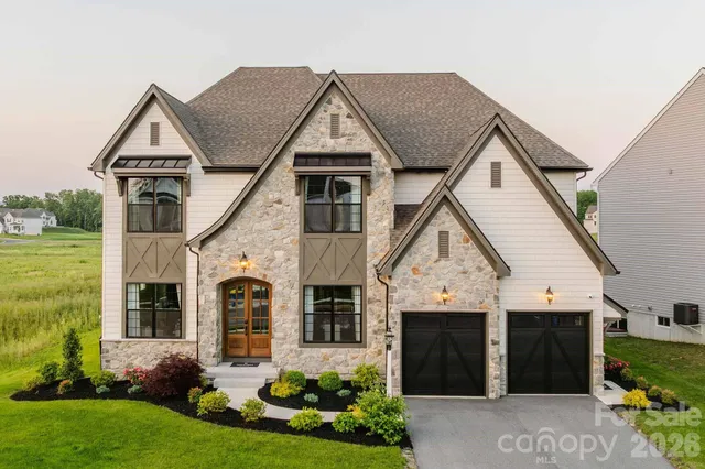 a view of a white house next to a yard with big trees