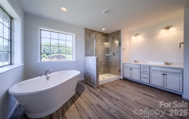 a spacious bathroom with a double vanity sink a mirror and a bathtub