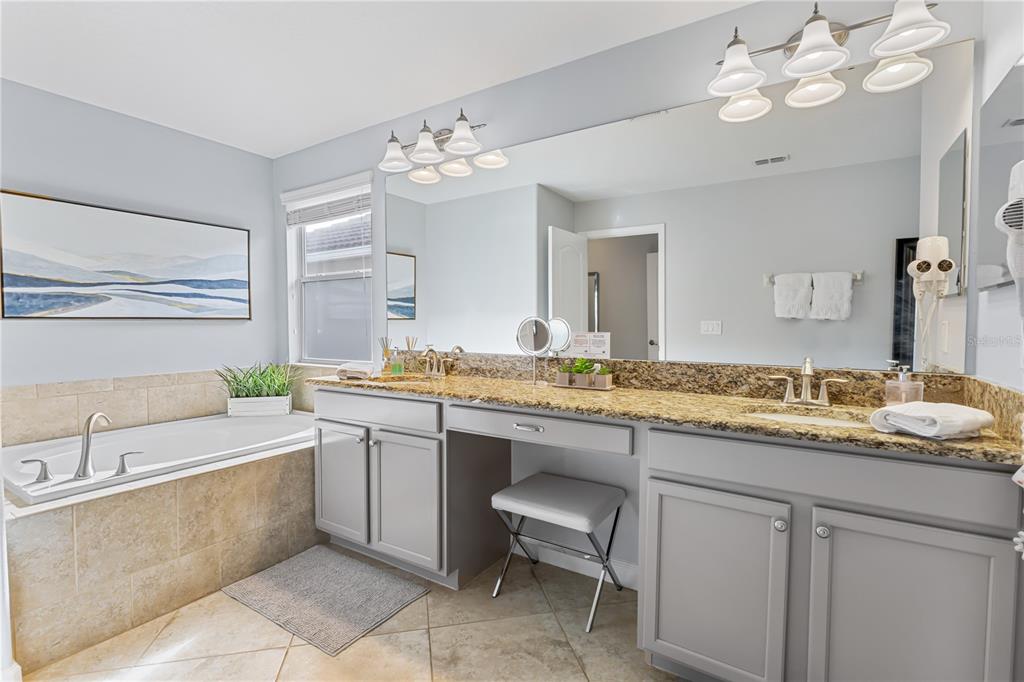 9006 Majesty Palm Road Kissimmee, FL 34747 - Photo 41 of 56 a bathroom with a granite countertop sink a large mirror and a bathtub