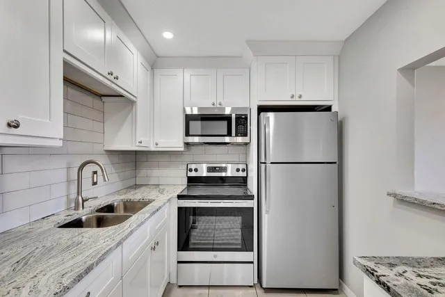 a kitchen with refrigerator a stove a sink and cabinets