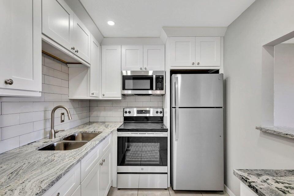a kitchen with refrigerator a stove a sink and cabinets