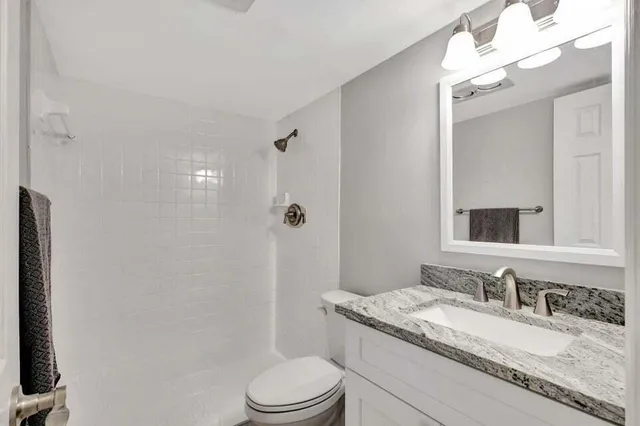 a bathroom with a granite countertop sink a toilet and a mirror