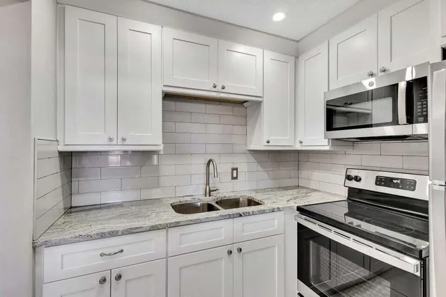 a kitchen with granite countertop white cabinets and stainless steel appliances