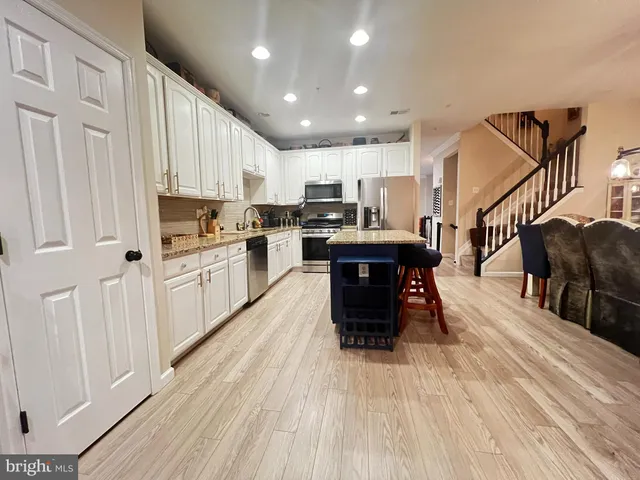 a kitchen with stainless steel appliances granite countertop a refrigerator a stove top oven a sink dishwasher and white cabinets with wooden floor