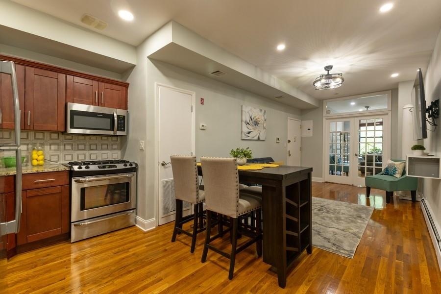100 Ralph Avenue, Unit 2L Brooklyn, NY 11221 - Photo 7 of 15 a kitchen with stainless steel appliances a table chairs and a refrigerator