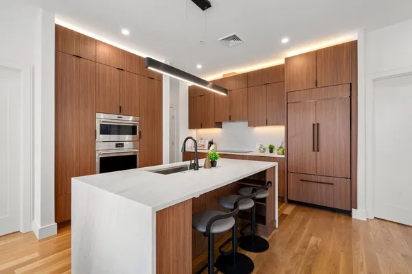 a kitchen with stainless steel appliances a sink a microwave a refrigerator and wooden floor