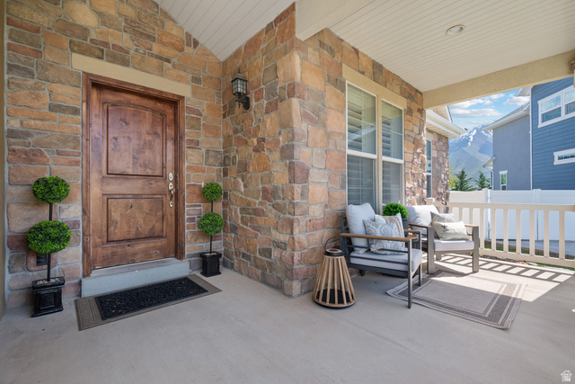 927 Iris Lane Mapleton, UT 84664 - Photo 2 of 31 Stone facade, wood-panel entry door, covered porch, exterior wall sconce, white railing