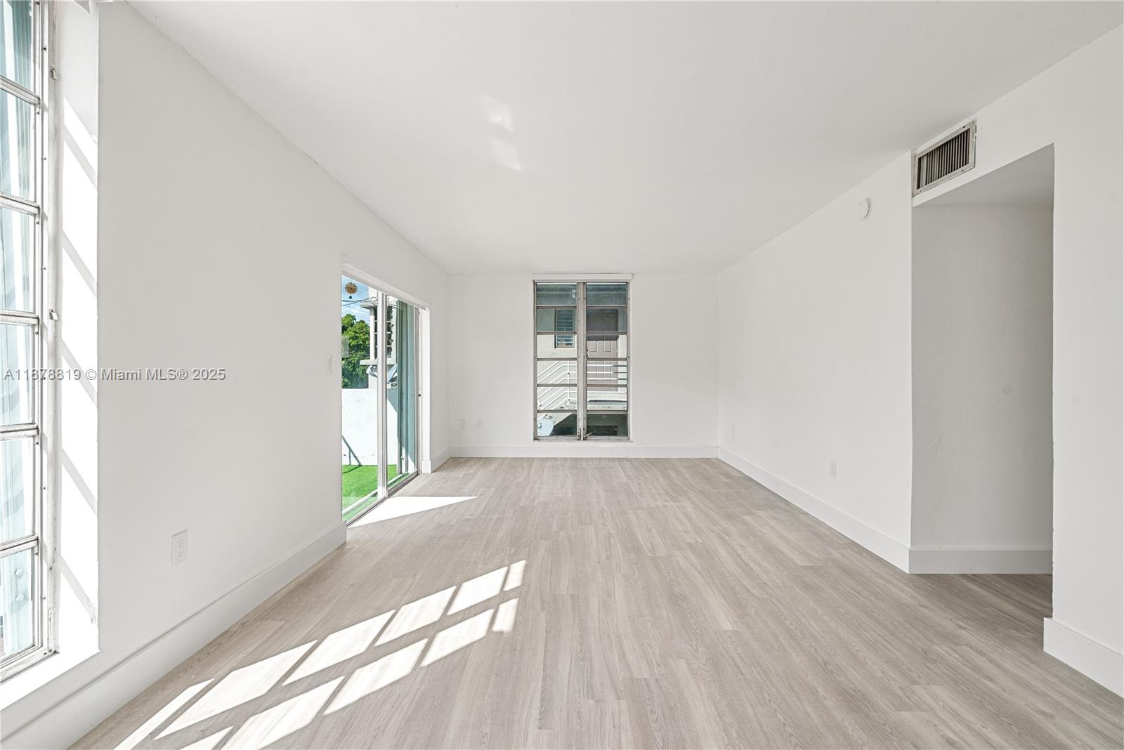 8305 Crespi Boulevard, Unit 2D Miami Beach, FL 33141 - Photo 3 of 33 a view of an empty room with wooden floor and a window