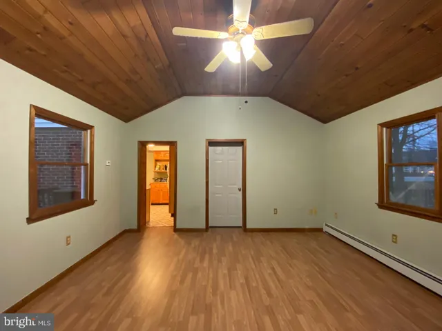 an empty room with wooden floor chandelier fan and windows