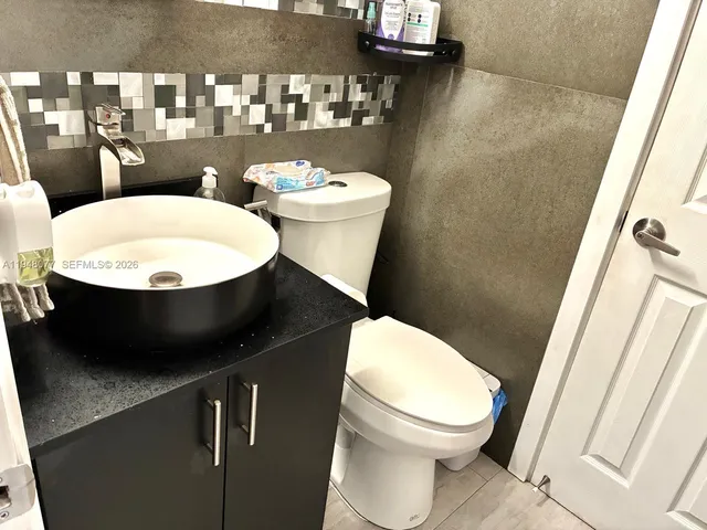 a white toilet sitting next to a bathroom sink and a mirror