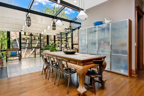 a dining hall with stainless steel appliances kitchen island granite countertop a table chairs and a oven