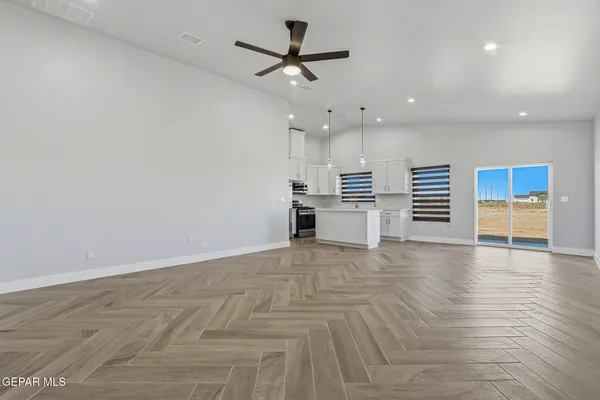 an empty room with wooden floor and a ceiling fan