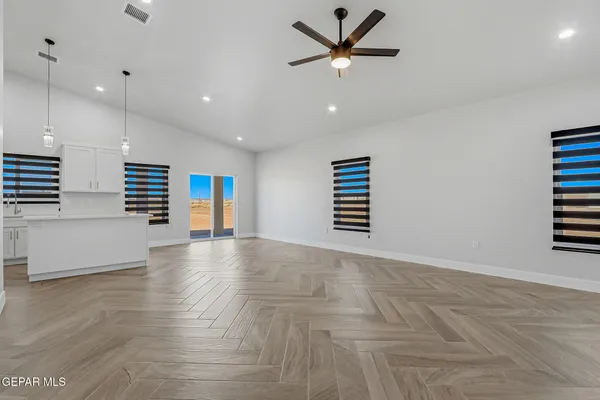 an empty room with wooden floor and a ceiling fan