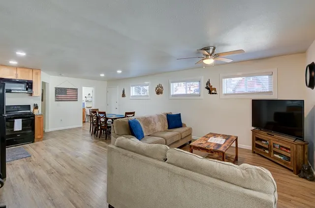 a kitchen with stainless steel appliances granite countertop a stove a refrigerator a kitchen island a dining table and chairs with wooden floor