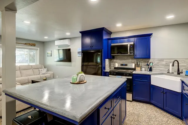a kitchen with stainless steel appliances kitchen island granite countertop a table chairs sink and cabinets