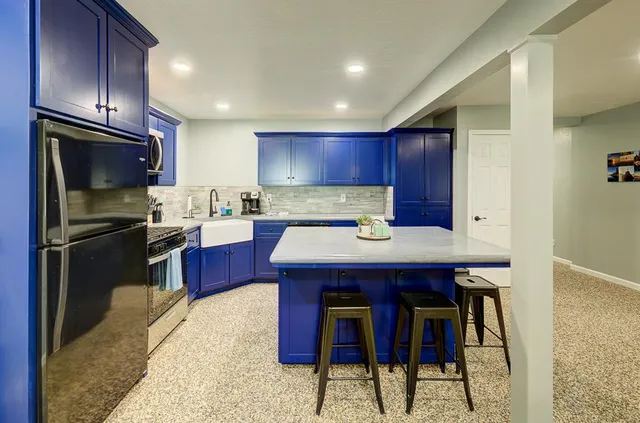 a kitchen with stainless steel appliances kitchen island granite countertop a refrigerator a stove and a sink with wooden cabinets