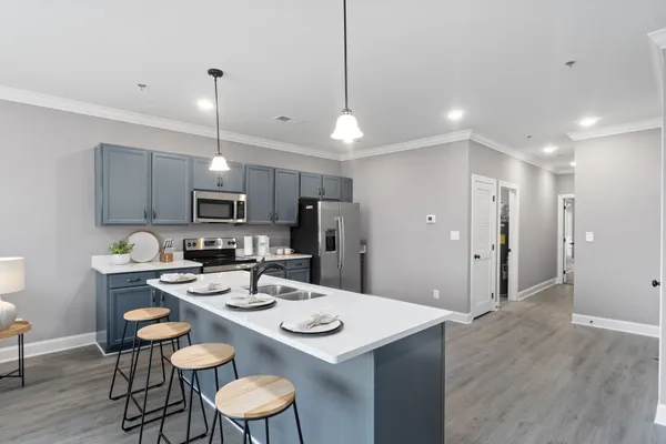 a kitchen with stainless steel appliances kitchen island granite countertop a dining table chairs and microwave