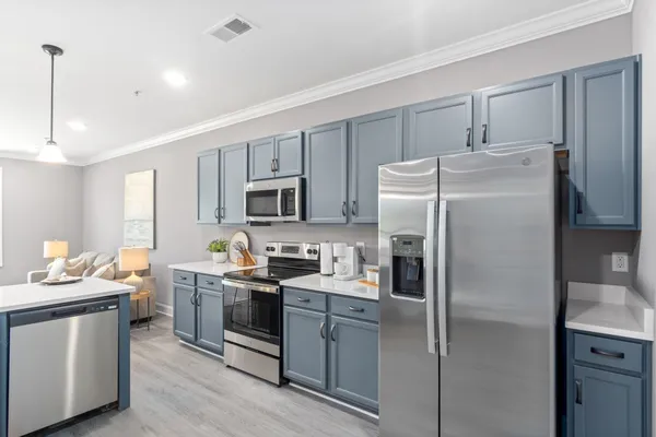 a kitchen with stainless steel appliances granite countertop a refrigerator stove a sink and white cabinets with wooden floor