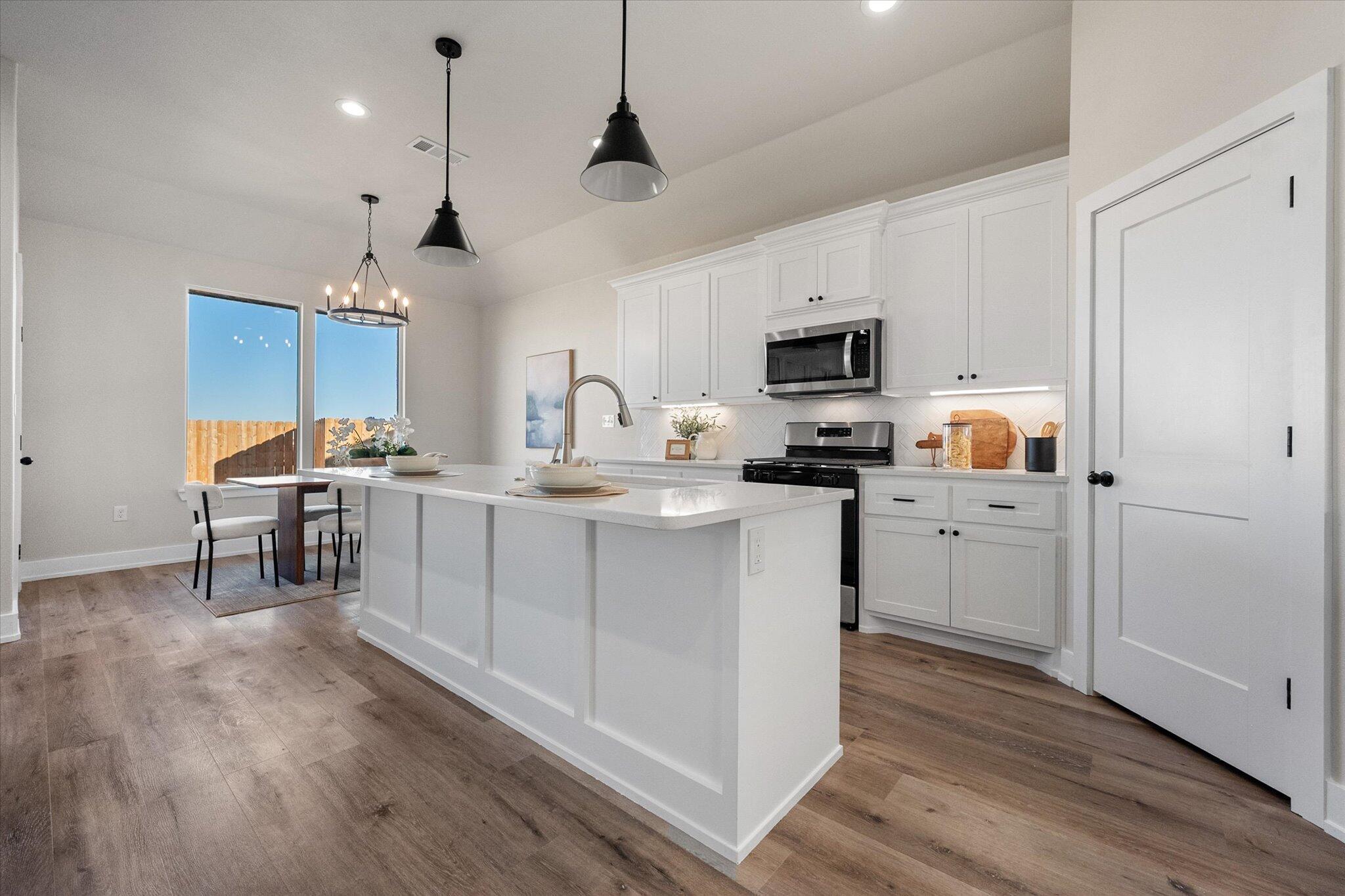 1404 Durham Avenue Wolfforth, TX 79382 - Photo 11 of 34 a kitchen with kitchen island granite countertop a sink cabinets and wooden floor