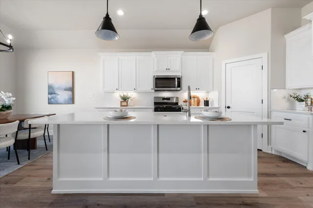 a kitchen with kitchen island granite countertop a sink cabinets and wooden floor