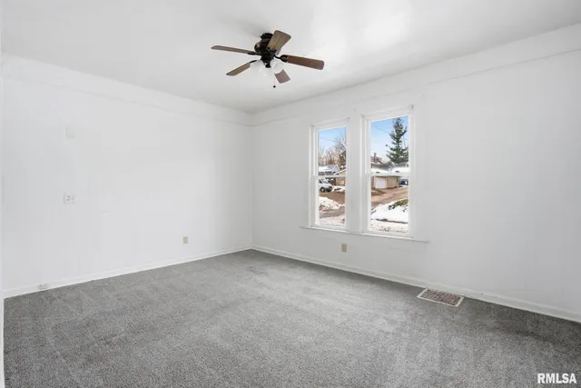 an empty room with windows and ceiling fan