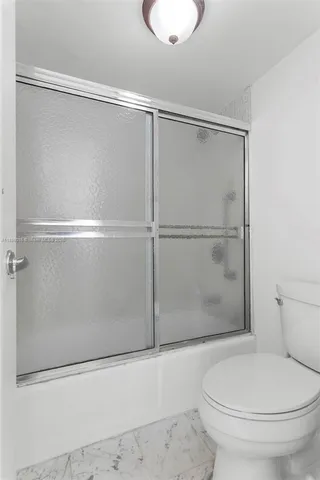 a white toilet sitting next to a shower